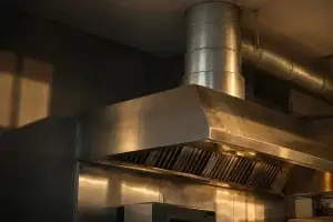 Conduit et hotte en cuisine professionnelle en métal inoxydable avec conduit d’évacuation au plafond.